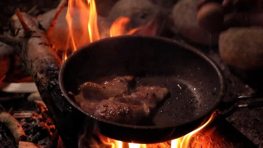 meat cooking in a pan on an open fire