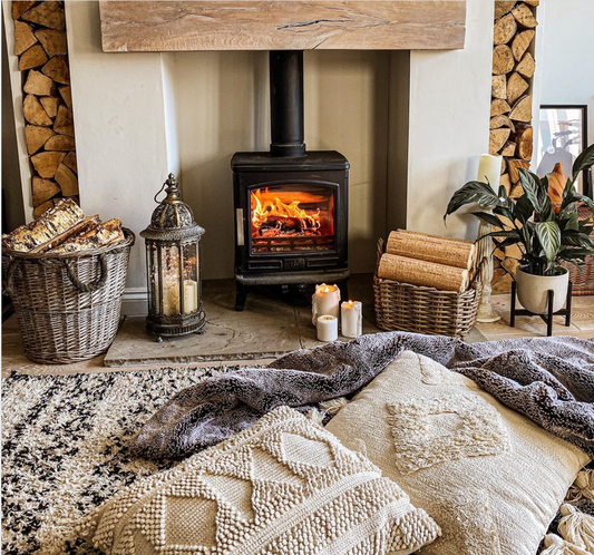 An indoor wood burner in a rustic lounge, surrounded by heat logs